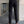 Man in zwarte broek en bruine loafers, staand op grijze tegelvloer. Stijlvolle herenkleding, zakelijke outfit, moderne mode.
