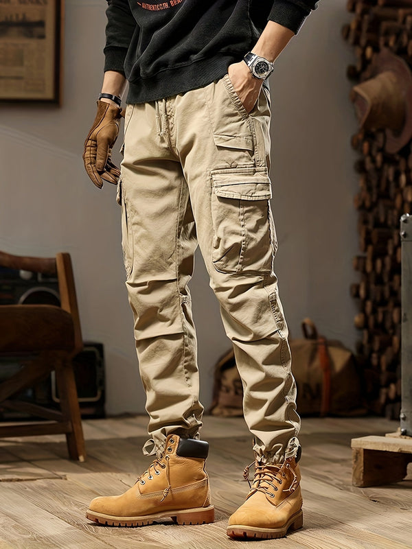 Beige cargobroek met meerdere zakken, gedragen met bruine werkschoenen en zwarte trui. Stijlvolle herenkleding voor casual en outdoor activiteiten.