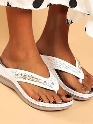 Witte orthopedische slippers voor dames, comfortabel en stijlvol, met perforaties en decoratieve details, ideaal voor zomerse outfits en dagelijks gebruik.