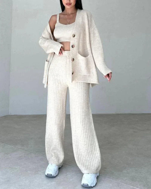 Vrouw in crèmekleurige gebreide set met vest, top en broek, gecombineerd met witte sneakers. Modieuze dameskleding, comfortabele herfstoutfit.