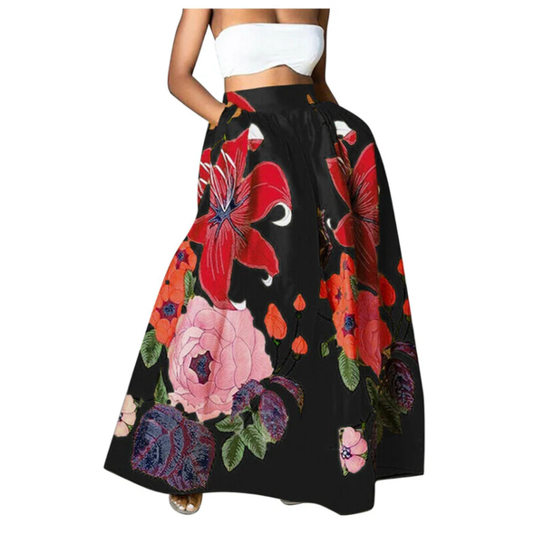 Vrouw in witte crop top met lange zwarte rok met kleurrijke bloemenprint, waaronder rode en roze bloemen. Trendy damesmode, zomeroutfit.