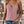 Vrouw in roze kanten top en denim shorts voor bakstenen muur, trendy zomeroutfit, casual mode, boho sieraden, stijlvolle kleding.