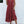 Vrouw in rode zomerjurk met knopen, staand tegen witte muur. Casual mode, boho-stijl, sandalen, zomerkleding, damesjurk, trendy outfit.