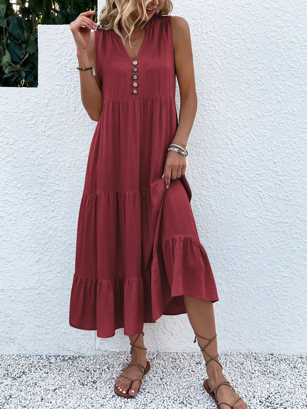 Vrouw in rode zomerjurk met knopen, staand tegen witte muur. Casual mode, boho-stijl, sandalen, zomerkleding, damesjurk, trendy outfit.