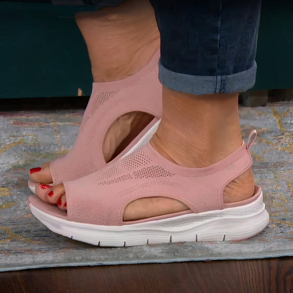 Roze sandalen met open teen en dikke zool, gedragen door een persoon op een tapijt. Comfortabele zomerschoenen voor dames, modieus en casual.