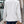 Vrouw in witte geribbelde trui en blauwe jeans, houdt beige clutch vast. Modieuze herfstoutfit, casual straatstijl, stedelijke achtergrond.