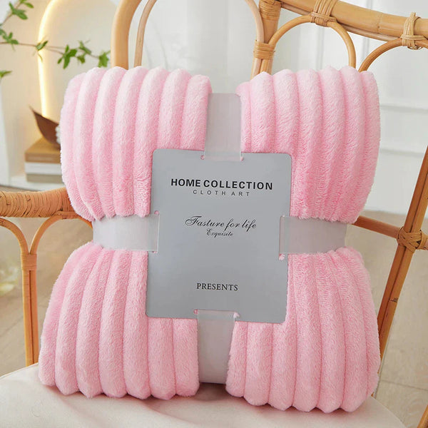 Zachte roze fleece deken, Home Collection, op rotan stoel. Perfect voor interieurdecoratie, comfort en warmte. Ideaal voor woonkamer of slaapkamer.