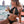 Vrouw in zwarte bikini met drankje op strand, genietend van zomervakantie. Perfecte stranddag, zon, zee, en ontspanning. Luxe strandmode.