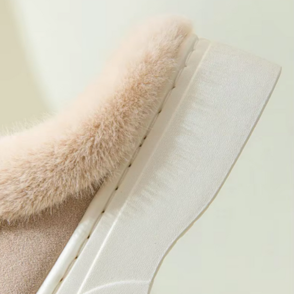 Beige suède pantoffel met witte rubberen zool en zachte, pluizige voering. Comfortabele dameshuisschoen, ideaal voor winterse warmte.