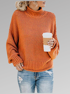 Oranje gebreide trui met col, gedragen door vrouw met blond haar, gecombineerd met gescheurde jeans en een kartonnen koffiebeker. Trendy herfstmode.