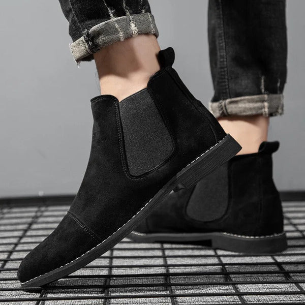 Zwarte suède Chelsea boots voor heren, met elastische zijkanten en gestikte details, gedragen met opgerolde jeans. Stijlvolle herenschoenen.