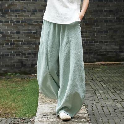 Vrouw draagt losse, lichtgroene linnen broek, casual mode, comfortabele wijde pijpen, buiten op stenen pad, trendy zomeroutfit.