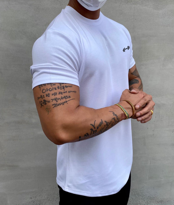 Man in wit T-shirt met tatoeages op armen, draagt een mondkapje. Casual mode, streetwear, tatoeage kunst, gezondheidsmaatregelen.