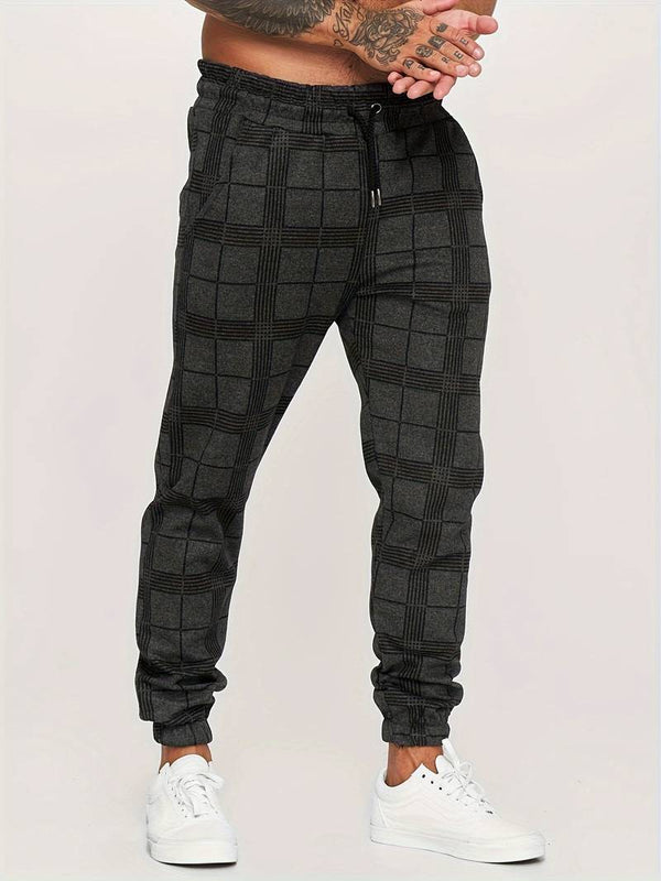 Grijze geruite joggingbroek voor heren, casual streetwear, elastische tailleband, comfortabele pasvorm, gecombineerd met witte sneakers.