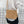 Gehaakte schoudertas van beige touw met geometrisch patroon, gedragen door persoon in witte blouse. Modieuze handtas, perfect voor casual outfits.