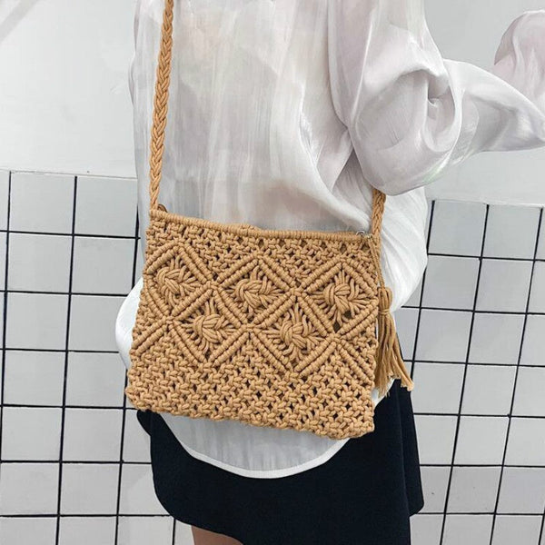 Gehaakte schoudertas van beige touw met geometrisch patroon, gedragen door persoon in witte blouse. Modieuze handtas, perfect voor casual outfits.
