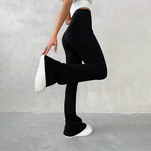 Vrouw in zwarte flared broek en witte sneakers, zijaanzicht. Modieuze dameskleding, comfortabele pasvorm, casual stijl.