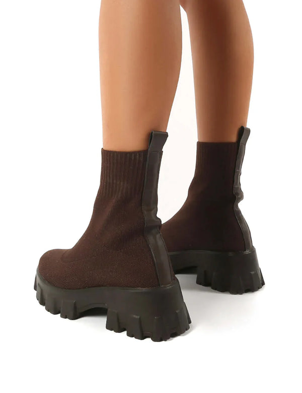 Bruine enkellaarsjes met dikke zwarte zool, sokstijl, achteraanzicht. Trendy damesmode, comfortabele herfst- en winterlaarzen.