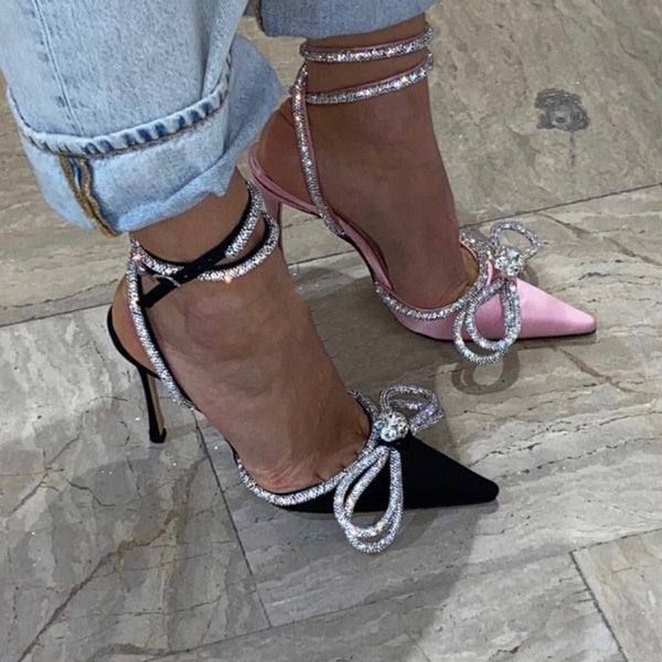 Dameshakken met strass en strik, zwart en roze, op marmeren vloer. Trendy schoenen, elegante stiletto's, modieuze accessoires.