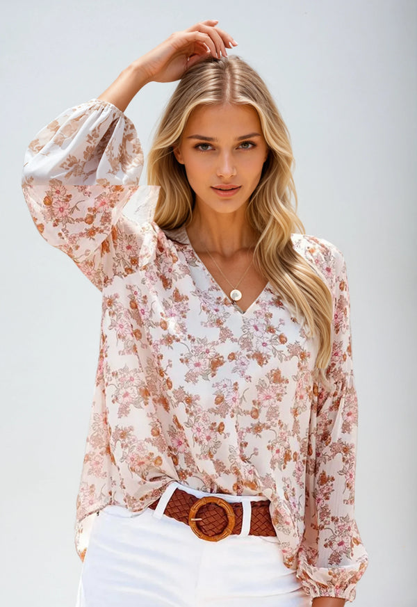 Vrouw in bloemenblouse met lange mouwen, V-hals en witte broek. Modieuze dameskleding, casual stijl, geschikt voor lente en zomer.