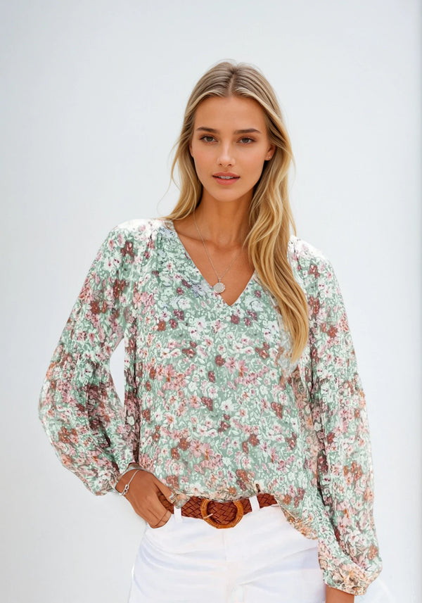 Vrouw draagt bloemenblouse met lange mouwen, V-hals en pastelkleuren. Perfect voor lente- en zomermode. Trendy dameskleding.