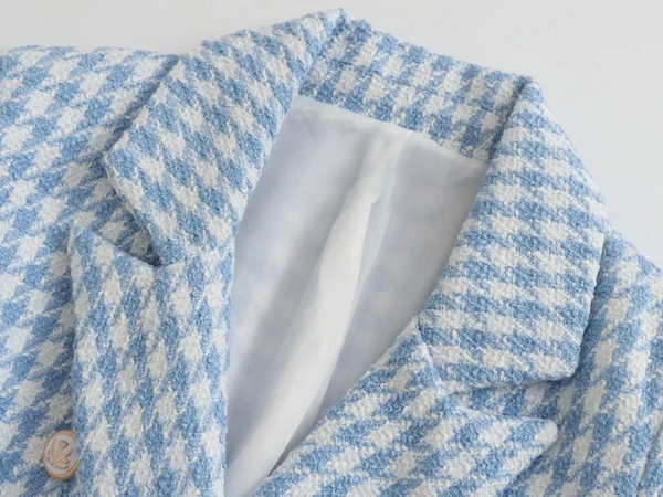 Blauw-wit geruite tweed blazer met reverskraag, close-up. Modieuze damesjas, elegant ontwerp, hoogwaardige stof, trendy kledingstuk.