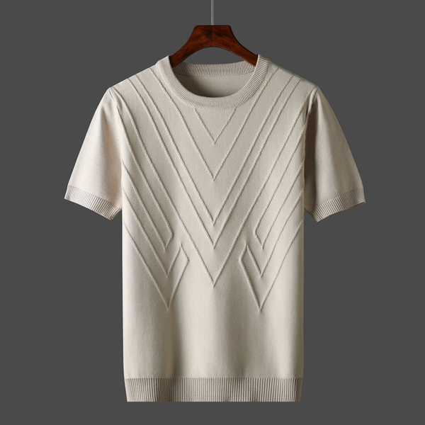 Crèmekleurige gebreide trui met korte mouwen en geometrisch patroon, hangend aan houten hanger. Stijlvolle herenkleding, perfect voor casual outfits.