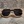 Gouden, geometrische zonnebril met donkere glazen op een ruwe, grijze achtergrond. Trendy unisex accessoire, modieuze zonnebril voor zomerstijl.