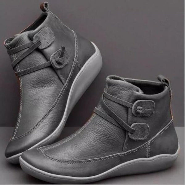 Grijze leren damesenkelboots met gespsluiting, comfortabele zool en modern design. Perfect voor casual en stijlvolle herfst- en winteroutfits.