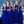 Vijf vrouwen in koningsblauwe jurken met champagneglazen, poseren buiten met een zeezicht. Bruidsmeisjes, elegante avondjurken, bruiloft.
