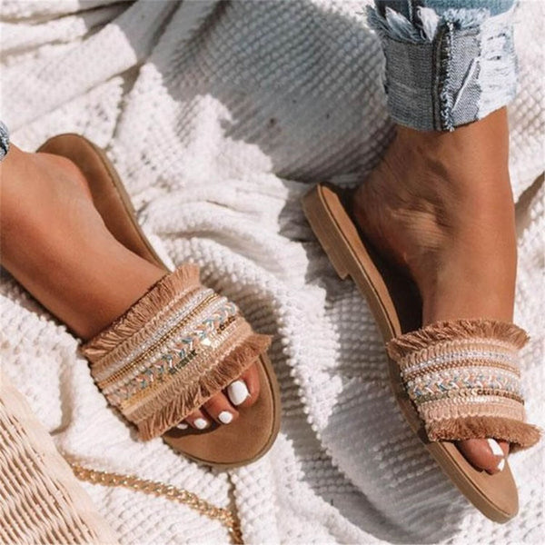 Beige sandalen met franjes en kralen, gedragen op een witte deken. Perfect voor zomerse outfits. Comfortabele en stijlvolle damesmode.