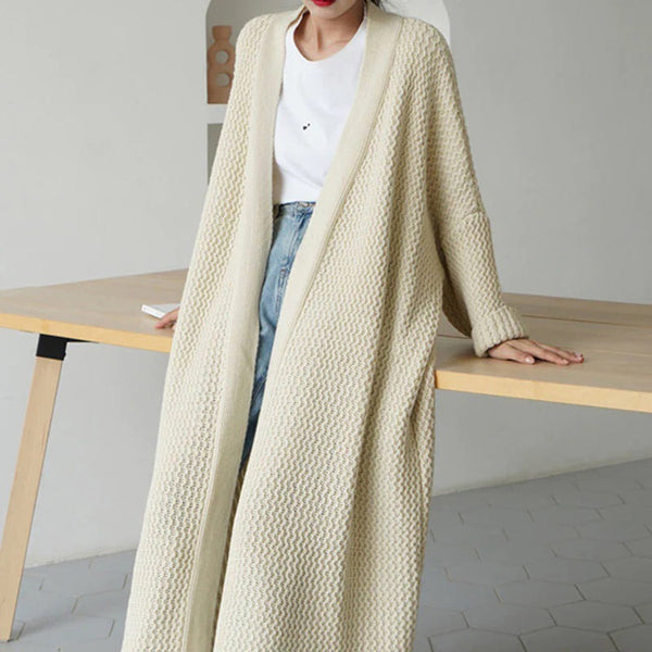 Beige gebreide lange cardigan, casual stijl, gedragen door een persoon, gecombineerd met een witte top en blauwe jeans, moderne minimalistische achtergrond.