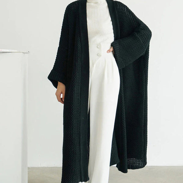 Zwarte gebreide lange cardigan, damesmode, minimalistisch design, over een witte coltrui en broek, stijlvolle herfst- en winterkleding.