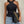 Vrouw in zwarte haltertop met gewatteerde zwarte tas met gouden ketting, casual outfit, denim jeans, modieuze dameskleding.