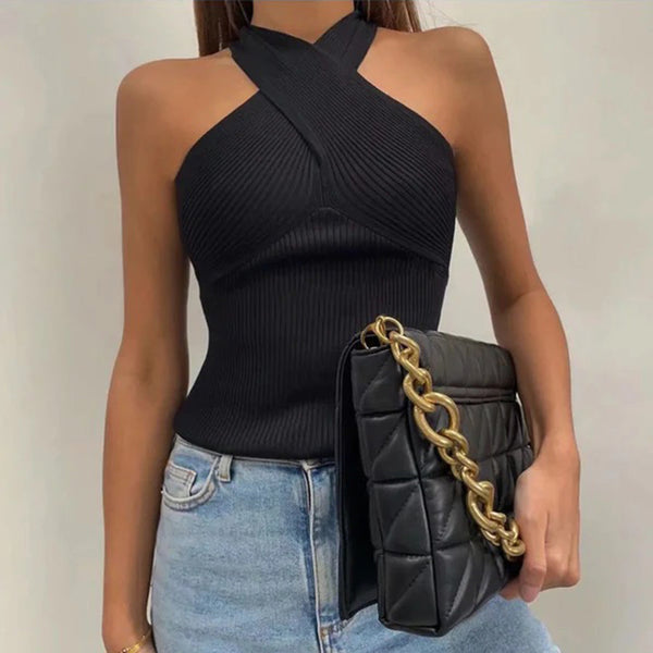 Vrouw in zwarte haltertop met gewatteerde zwarte tas met gouden ketting, casual outfit, denim jeans, modieuze dameskleding.