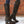 Zwarte leren laarzen met studs, hoge hak en ritssluiting, tegen een bakstenen muur. Trendy dameslaarzen, westernstijl, modieuze schoenen.