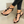 Zwarte sandalen met gouden details en zwarte stenen, gedragen door een vrouw met witte nagellak. Stijlvolle zomerschoenen voor dames.
