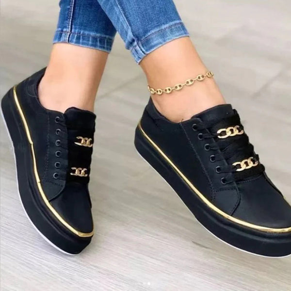 Zwarte dames sneakers met gouden kettingdetails en witte zolen, gedragen met blauwe jeans. Trendy casual schoenen voor dagelijks gebruik.