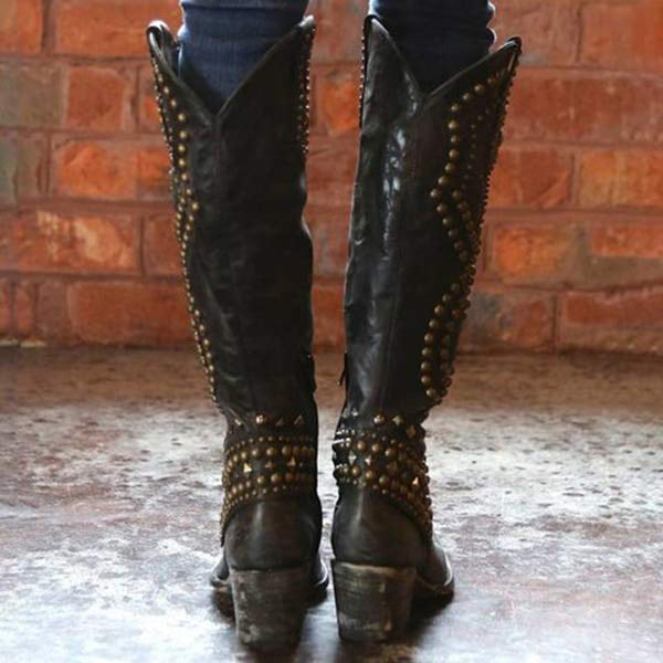 Zwarte leren cowboylaarzen met studs, gedragen door persoon voor bakstenen muur. Trendy westernstijl, vintage look, damesmode.
