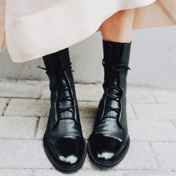 Zwarte leren veterlaarzen voor dames, glanzend en stijlvol, op een stenen ondergrond. Perfect voor herfstmode en casual outfits.