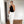 Vrouw in stijlvolle zwarte haltertop en witte broek, poseert voor een spiegel. Moderne mode, minimalistisch design, trendy outfit.