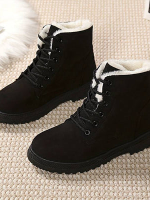 Zwarte winterlaarzen met veters en warme voering op beige tapijt. Ideaal voor koude seizoenen. Comfortabele en stijlvolle dameslaarzen.