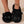 Zwarte pluche pantoffels met kattengezicht, groene ogen en oren, gedragen door een persoon. Comfortabele dameshuisschoenen, trendy en warm.