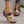 Vrouw draagt kleurrijke sandalen met bloemenpatroon en sleehak, perfect voor zomermode. Comfortabele open teen design, ideaal voor casual outfits.