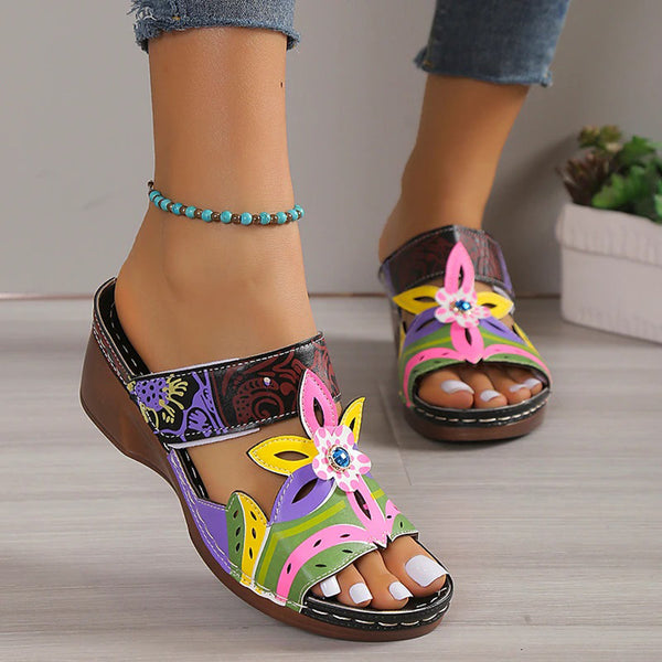 Vrouw draagt kleurrijke sandalen met bloemenpatroon en sleehak, perfect voor zomermode. Comfortabele open teen design, ideaal voor casual outfits.