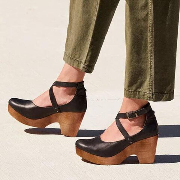 Zwarte leren damesklompen met houten hak, gedragen met groene broek. Modieuze comfortabele schoenen, ideaal voor casual en trendy outfits.