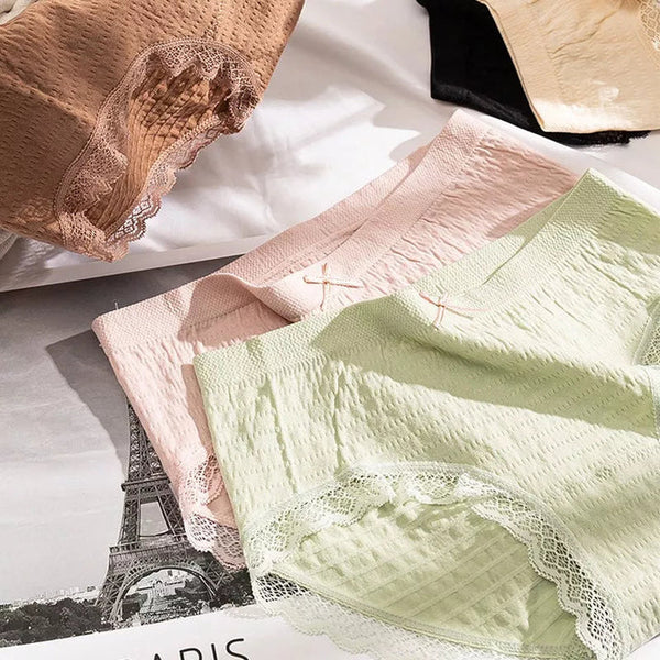 Damesondergoed in pastelkleuren met kanten details, liggend op een bed. Comfortabele slipjes, modieuze lingerie, zachte stoffen.