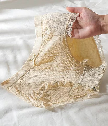 Hand houdt crèmekleurige kanten damesonderbroek vast op wit laken. Comfortabel, ademend ondergoed, perfecte pasvorm, hoge taille.