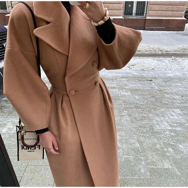 Vrouw in stijlvolle bruine wollen jas met dubbele rij knopen, draagt een modieuze handtas. Wintermode, elegante dameskleding, straatstijl.