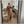 Vrouw in stijlvolle bruine trenchcoat en wijde broek, poseert voor spiegel in modern interieur. Trendy mode, herfstkleding, minimalistisch design.